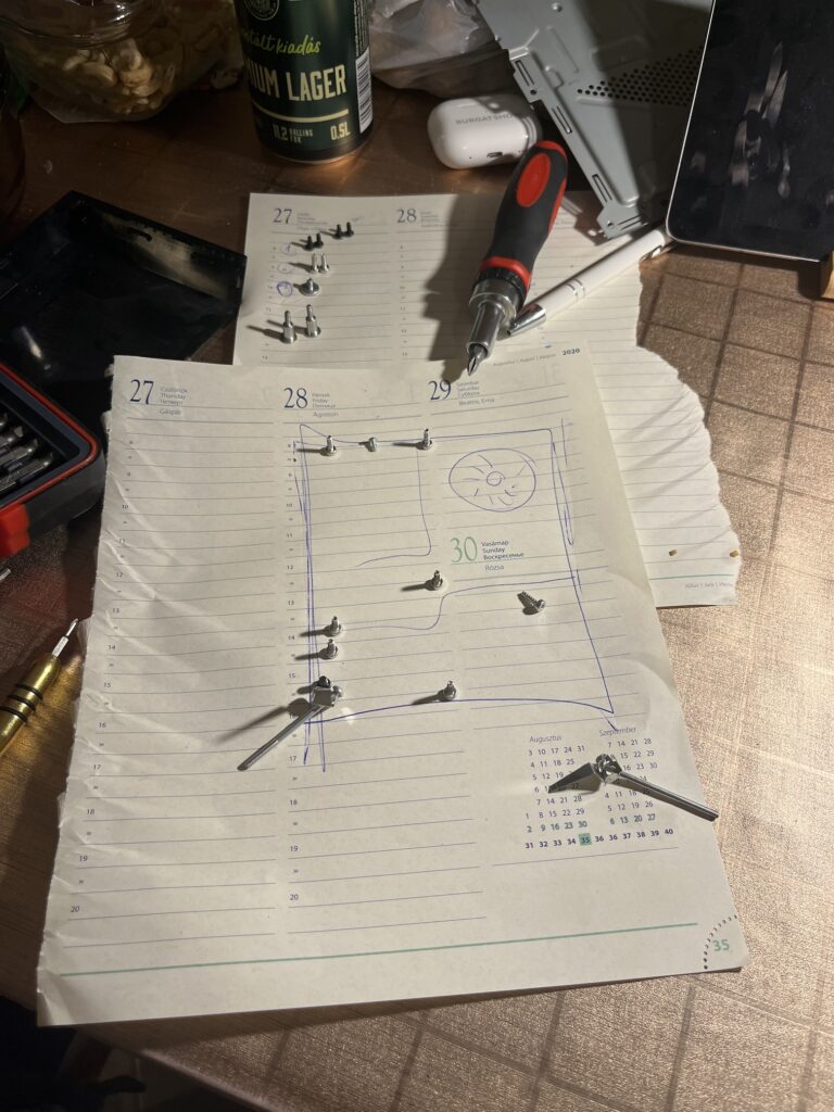 Papírlap egy sematikus ábrával, hogy a Play Station 4-ből kivett csavarok helyét szemléltesse.